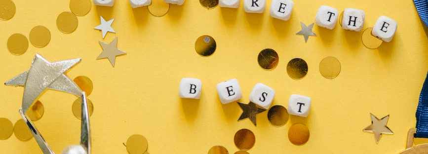 You are the best! Yellow background with gold glitter, gold medal, and star trophy.